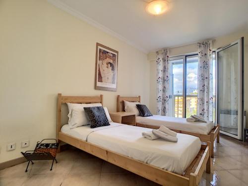 deux lits dans une chambre avec une grande fenêtre dans l'établissement Nestor&Jeeves - PALAIS RENOIR - By sea - Free parking, à Nice