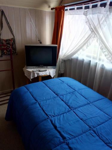 a bedroom with a blue bed and a television at Hospedaje Alicia Acuna in Quepe