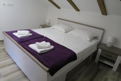 a white bed with two towels on top of it at Family Apartment in Baška