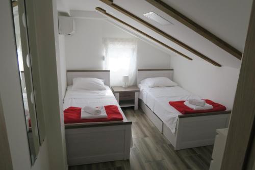 two beds in a small room with red sheets at Family Apartment in Baška