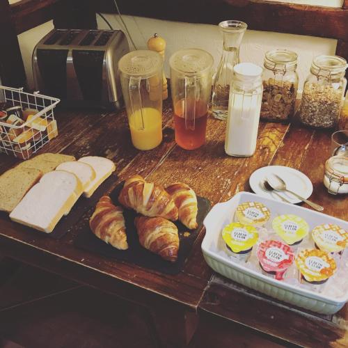 a table with bread and croissants and other breakfast foods at The New Court Inn in Usk