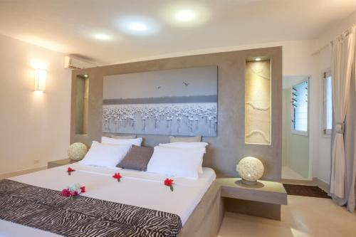 a bedroom with a large white bed with red flowers on it at The Kasa Malindi in Malindi