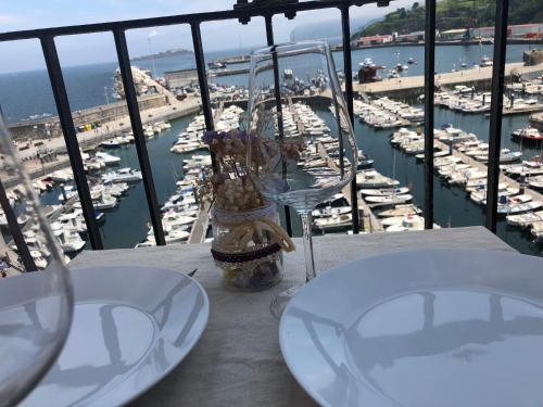 a table with two glasses and a view of a marina at Torrontero con vistas al mar in Bermeo