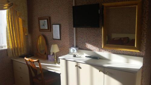 a room with a dresser and a television on the wall at White Lodge Guest House in Skegness