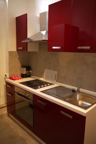 - une cuisine équipée de placards rouges, d'une cuisinière et d'un évier dans l'établissement Appartements des Teinturiers, à Avignon