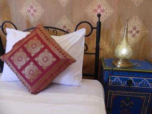 a bed with two pillows and a lamp on a night stand at Morocco Deluxe Camp - Assif n'Itrane in Lac Yasmins
