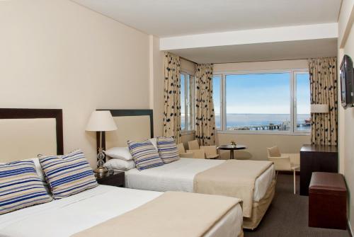 um quarto de hotel com duas camas e uma grande janela em Hotel Península Valdés em Puerto Madryn