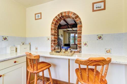 a kitchen with a counter with two wooden stools at Bwthyn Banw in Meifod