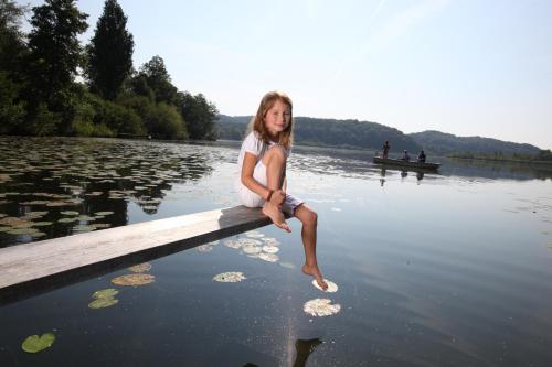 a young girl sitting on a dock in the water at Landhotel Moorhof in Franking