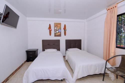 two beds in a room with white walls at Hotel Alto de los Andaquies in San Agustín