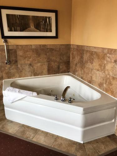 a white bath tub in a bathroom with a tile wall at AmericInn by Wyndham Fargo Medical Center in Fargo