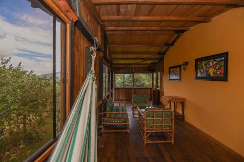 a room with a balcony with chairs and windows at Hotel Alto de los Andaquies in San Agustín