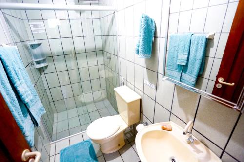 La salle de bains est pourvue de toilettes, d'un lavabo et de serviettes bleues. dans l'établissement Cabanas Jurerê, à Florianópolis
