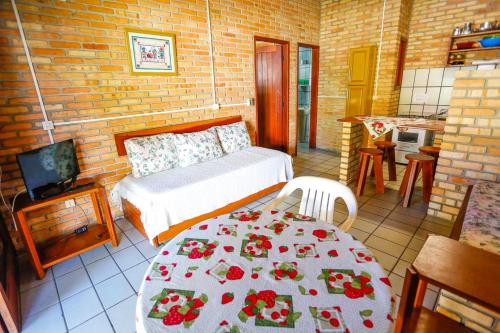 Cet appartement comprend une chambre avec un lit et une table ainsi qu'une cuisine. dans l'établissement Cabanas Jurerê, à Florianópolis