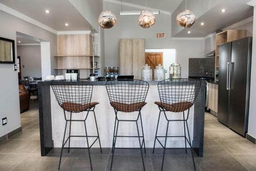 eine Küche mit drei Barhockern an einer Theke in der Unterkunft @Greys Guesthouse in Bloemfontein