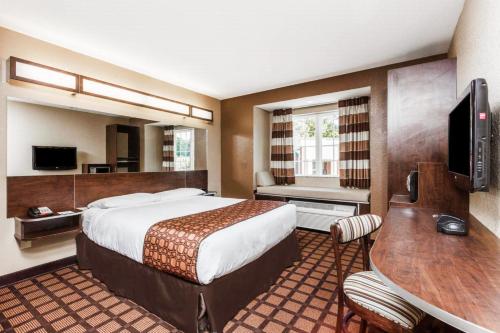 a hotel room with a bed and a desk and a table at Microtel Inn & Suites by Wyndham Macon in Macon