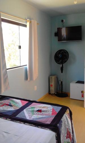 a bedroom with a bed with a window and a fan at Pousada Recanto dos Bentos in Itapeva