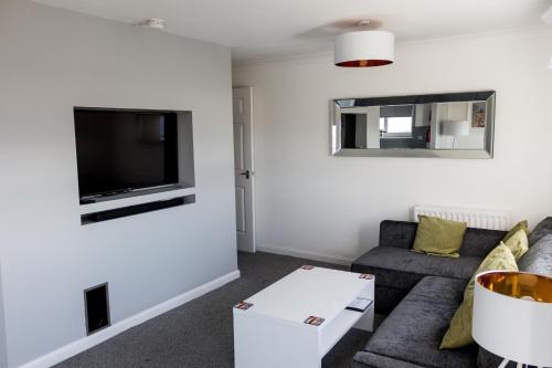 uma sala de estar com um sofá e uma televisão em No27 Ayr Beach - Coorie Doon Stays em Ayr