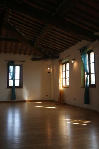 an empty room with two windows and a wooden floor at Podere Calcinaia in Castelnuovo Berardenga