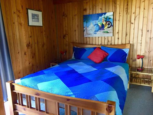 a bedroom with a blue bed in a wooden wall at Panoramic Drive Holiday House in Cape Bridgewater