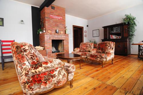 a living room with two chairs and a fireplace at Stara Szkoła w Harszu in Pozezdrze
