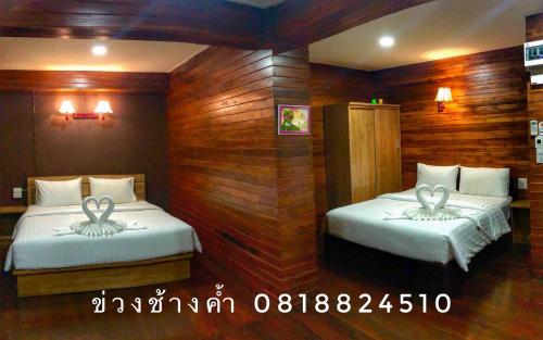 two beds in a room with wooden walls at Khuang Chang Kam in Nan