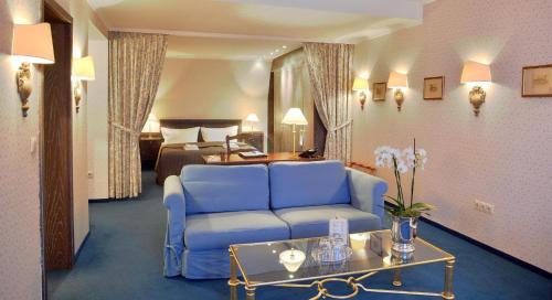 a living room with a blue couch and a bedroom at Stadthotel Patrizier in Schmalkalden