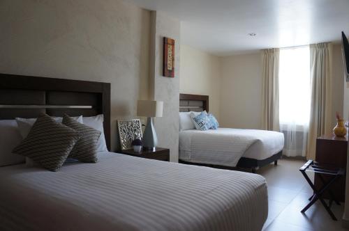 a hotel room with two beds and a window at Hotel Mirante Tlaxcala in Tlaxcala de Xicohténcatl