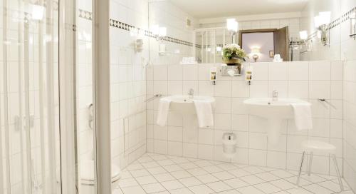 a white bathroom with two sinks and a shower at Stadthotel Patrizier in Schmalkalden