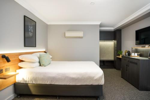 a small bedroom with a bed and a kitchen at Townhouse Hotel in Wagga Wagga