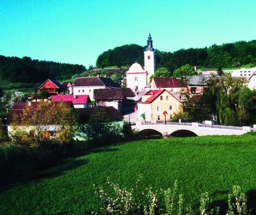 a village with a church and a bridge and a green field at Marinčič Inn in Škocjan