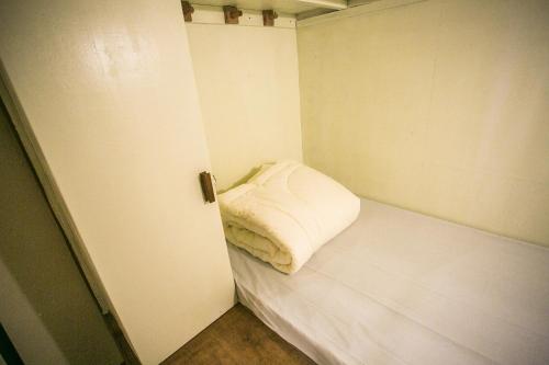 a small white room with a bed in it at Barn1920s Hostel in Vientiane
