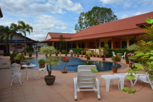 Baan Sabaijai Resort & Omsorgssenter في That Phanom: منتجع فيه مسبح وكراسي واشجار