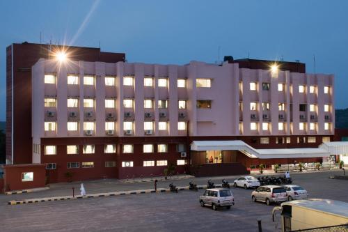 a large building with cars parked in a parking lot at Ramoji Sahara Shared Accommodation in Pedda Ambarpet