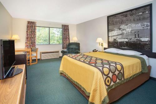 a hotel room with a bed and a flat screen tv at Super 8 by Wyndham Dewitt in De Witt