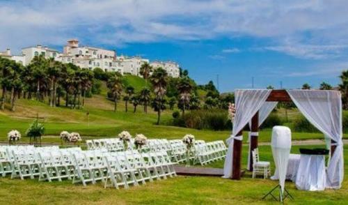 a group of white chairs and a table in a field at Real del Mar Golf Resort in Tijuana