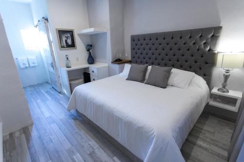 una camera da letto con un grande letto bianco con una grande testiera del letto di Hotel de Piedra a Bernal