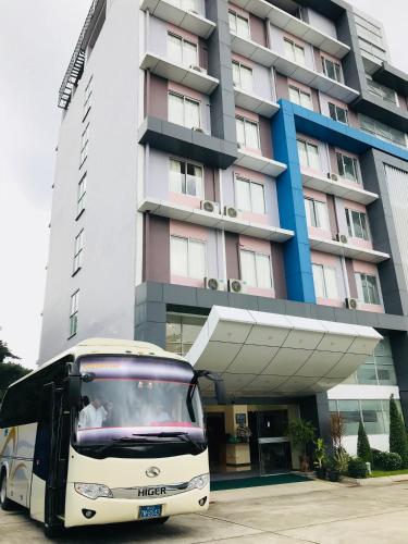 a white bus parked in front of a building at Hotel Broadway Yangon in Yangon