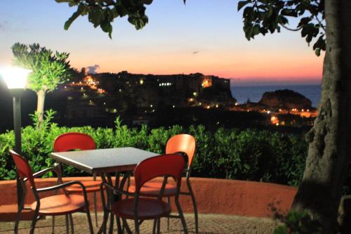 a table and chairs with a sunset in the background at Residence New Paradise in Tropea