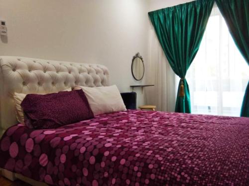 - une chambre avec un lit doté d'une couette violette et d'une fenêtre dans l'établissement Putra 1 Pool Homestay Bandar Seri Putra, à Kampong Sungai Buah