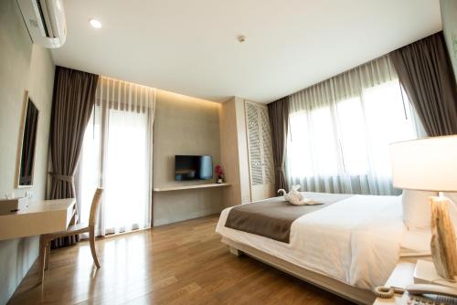 a bedroom with a bed and a desk and a tv at Chu Hotel in Chiang Mai