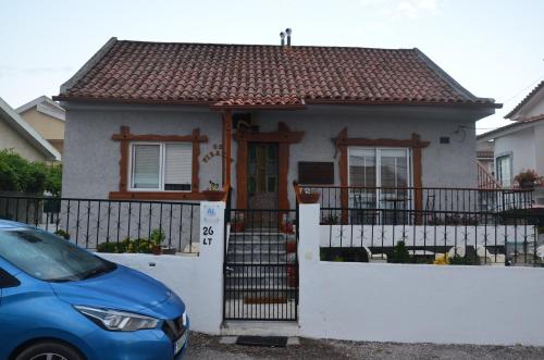 a small house with a gate and a blue car at Os Piratas in Charneca