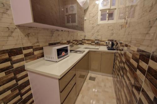 a small kitchen with a microwave on a counter at Golden Night Hotel in Najran