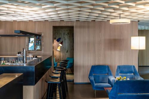 a lobby with a bar and blue chairs at Boutique-Hotel Ballguthof am Golfplatz in Lana