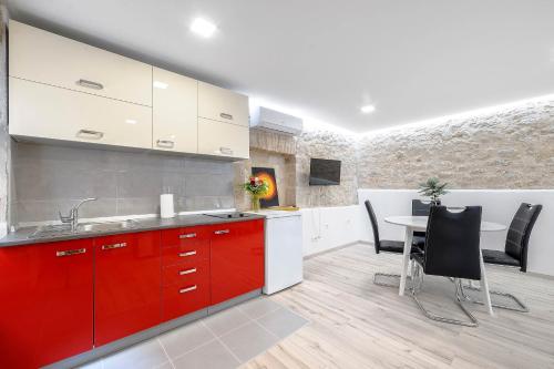 a kitchen with red cabinets and a table with chairs at Falcons Nest in Šibenik