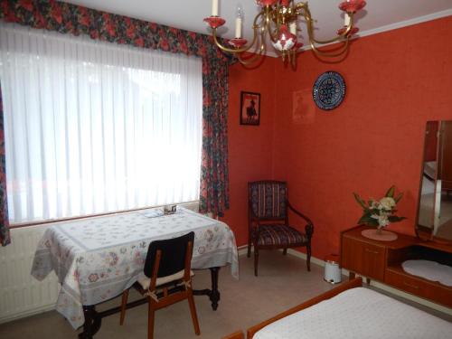 czerwony pokój ze stołem, oknem i krzesłem w obiekcie Au logis fleuri w mieście Francorchamps