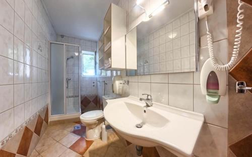 a white bathroom with a sink and a toilet at Apartments & Rooms Ruzmarin in Rogoznica