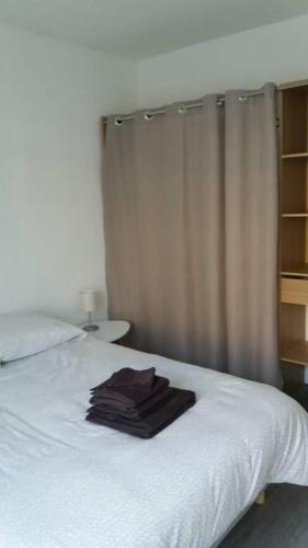 - une chambre avec un lit blanc et une serviette dans l'établissement Appartements Le Vivier 1er ou rez de chaussée avec parking, à Boulogne-sur-Mer