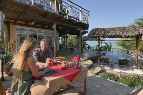 een man en een vrouw aan een tafel in een restaurant bij Villa Fleur De Lys in Makunduchi