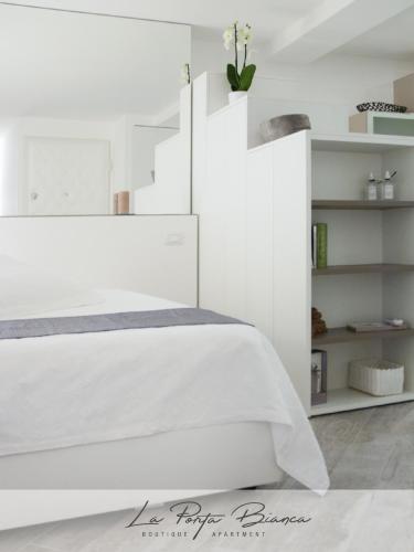 a bedroom with a white bed and white shelves at La Porta Bianca in Trieste